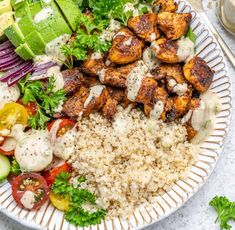 a white plate topped with chicken and rice next to salad on top of a table