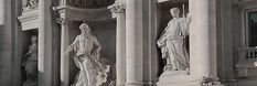 black and white photograph of statues on the side of a building in front of columns