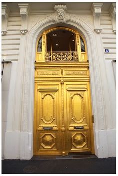 an ornate gold door in front of a white building