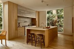 a kitchen with an island and two stools in front of the counter top that is surrounded by trees