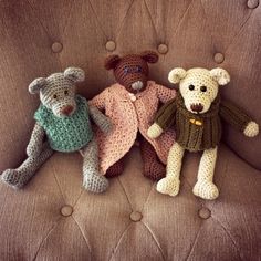 three crocheted teddy bears sitting on top of a brown couch next to each other