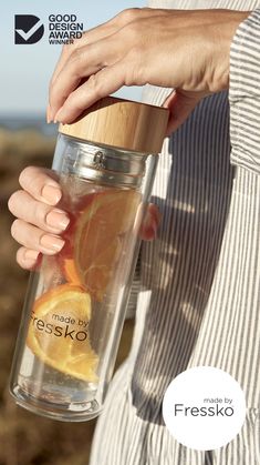 a woman holding a glass jar filled with oranges