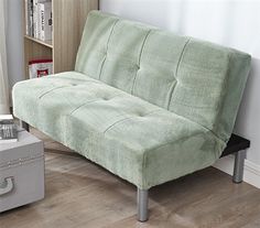 a living room with a futon couch and bookcase in the corner next to a window