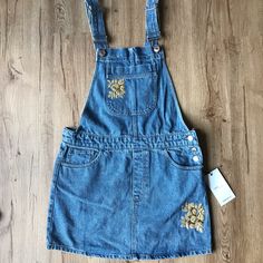 Brand New With Tags! Never Worn! Super Cute Denim Overalls With Golden Embroidered Flower Accents. The Embroidery Add Some Extra Style To The Traditional Overall Dress! Size: Small Spring Embroidered Denim Dress, Embroidered Denim Blue Dress, Embroidered Denim Dress For Summer, Embroidered Denim Dress For Spring, Spring Floral Embroidered Denim Dress, Spring Floral Embroidery Denim Dress, Embroidered Denim Dress In Blue, Embroidered Blue Denim Dress, Blue Embroidered Denim Dress