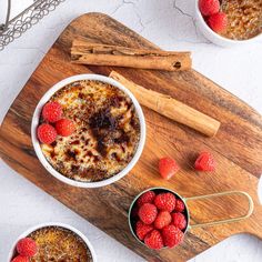 two bowls filled with oatmeal and raspberries next to cinnamon sticks