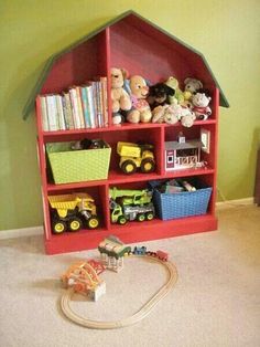 a red book shelf filled with lots of toys next to a toy train and truck