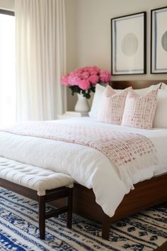 a bed with white sheets and pillows in a bedroom next to two framed pictures on the wall