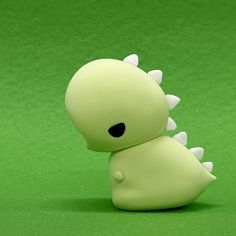 a green toy with white spikes on it's head sitting in front of a green background