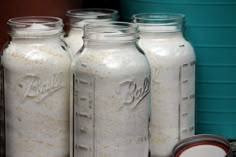 four jars are lined up next to each other and one has been filled with flour