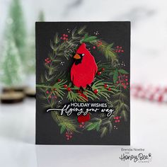 a christmas card with a cardinal sitting on a pine branch and holiday wishes below it