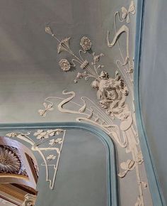 an ornately decorated ceiling with flowers and scrolls on it's side, painted in pale blue