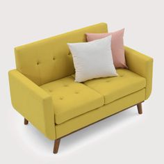 a yellow couch with two pillows on it's back and one pink pillow sitting on top of it