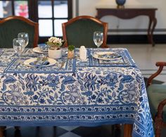 a blue and white table cloth on a dining room table set with place settings for two