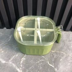 a green lunch box sitting on top of a stone floor