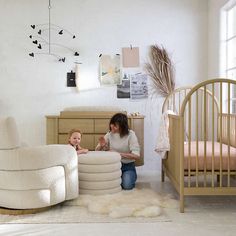 a woman and her child playing in a nursery room with white furniture on the floor