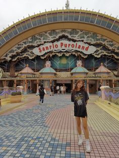 a woman standing in front of the entrance to sanrio purolland at disneyland world