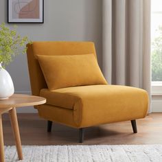 a yellow chair sitting next to a table with a vase and plant on top of it