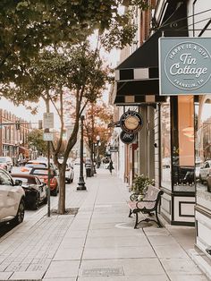 an empty street with parked cars on the side walk and trees in front of it