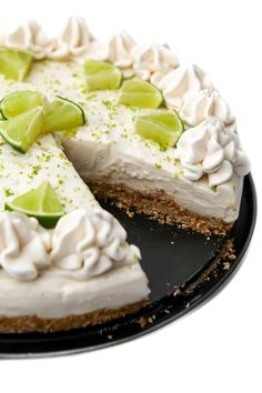 a pie with limes and whipped cream on top sits on a black platter