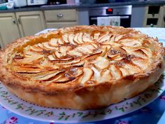 an apple pie sitting on top of a table next to a blue and white plate