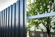 a close up of a metal fence with trees in the background