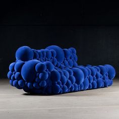 a blue couch sitting on top of a cement floor next to a black wall in an empty room