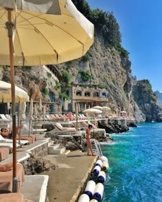 the beach is lined with umbrellas and lounge chairs near the water's edge