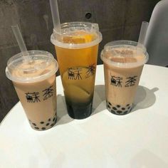 three drinks sitting on top of a table next to each other with straws in them