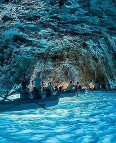 several people are rowing in a boat through a cave