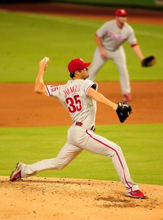 a baseball player pitching a ball on top of a field with other players in the background