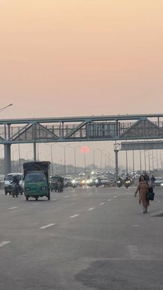 cars and trucks are driving on the road in front of an overpass at dusk