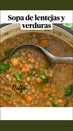 a pot filled with beans, carrots and spinach on top of a table