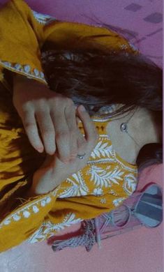 a woman laying on top of a bed wearing a yellow dress