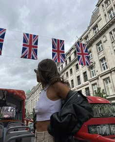 a woman standing in front of a bus with british flags hanging from it's roof