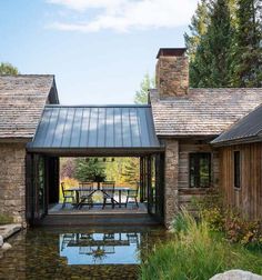 a house with a pond in front of it and stone walls around the back yard