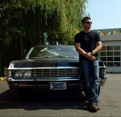 a man standing next to an old car