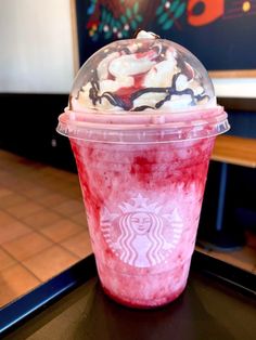 there is a drink with whipped cream on top and red liquid in the bottom, sitting on a table