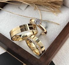 two gold wedding rings sitting on top of each other