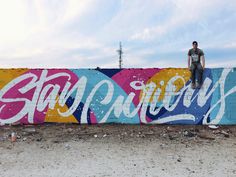 a man standing on top of a graffiti covered wall