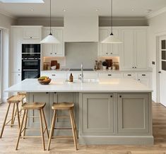 a large kitchen with white cabinets and wooden stools