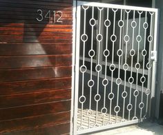 an iron gate is open on the side of a building that has a wooden door