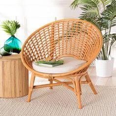 a wicker chair sitting on top of a rug next to a potted plant