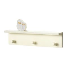 two owls sitting on top of a white shelf with three holes in the bottom and one is