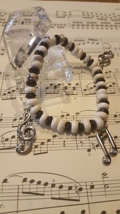 a white and black beaded bracelet with music notes on the sheet paper behind it