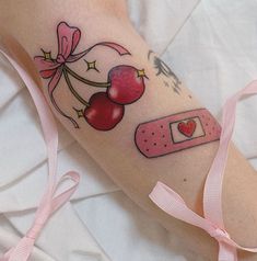 a woman's arm with tattoos on it that include cherries and a tape