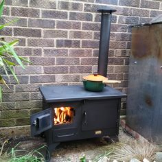 an outdoor wood burning stove in front of a brick wall