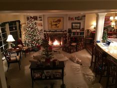 a living room filled with furniture and a fire place next to a christmas tree in front of a fireplace