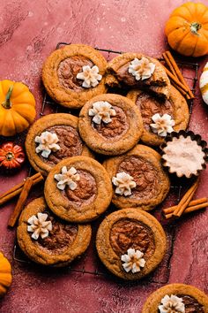 pumpkin pies and cinnamon cookies on a cooling rack next to small orange pumpkins