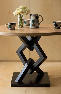 a wooden table topped with two cups and a vase filled with white flowers on top of it