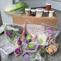 an assortment of vegetables and eggs are on the ground next to a cardboard box with food in it